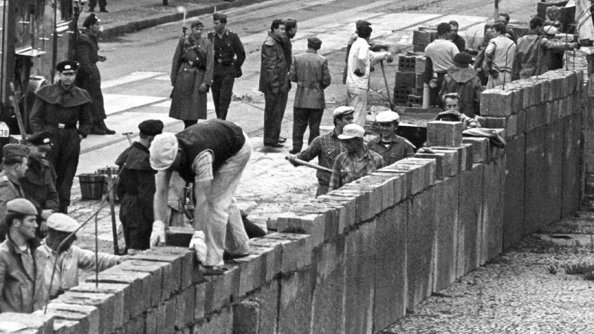 Black and White Image of workers laying concrete bricks of the Berlin Wall 1961.